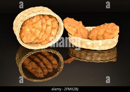 Mehrere runde, duftende Getreidekekse liegen in einem Strohkorb auf schwarzem Hintergrund. Stockfoto