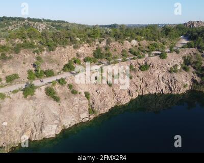 Felsige Ufer des Radon Lake an einem sonnigen Sommermorgen. Luftaufnahme eines alten überfluteten Granitsteinbruchs. Ein malerischer Teich. Stockfoto