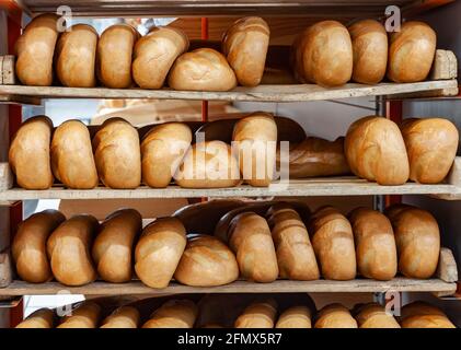 Viele frische, knackige Brote. Regale voll mit frischem goldenem Brot. Frisch gebackenes Brot liegt auf dem Regal zum Verkauf Stockfoto