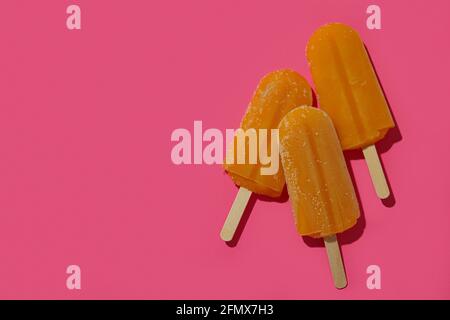 Mango- oder Karamell-Eis-Sticks auf rosa Hintergrund Stockfoto
