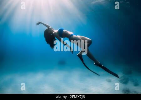 Attraktive Freitaucherin Frau mit Flossen tauchen tief unter Wasser im Meer. Stockfoto