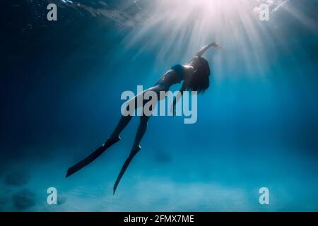 Attraktive Freitaucherin Frau mit Flossen tauchen tief unter Wasser im Meer. Stockfoto