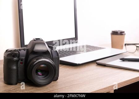 Termin für Fotografen Konzept. Draufsicht auf den Designer-Tisch mit pc-Laptop-Computer, Zeichentisch, Fotokamera, gelbe Memoaufkleber, Wecker, becher Stockfoto