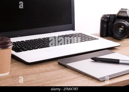 Termin für Fotografen Konzept. Draufsicht auf den Designer-Tisch mit pc-Laptop-Computer, Zeichentisch, Fotokamera, gelbe Memoaufkleber, Wecker, becher Stockfoto