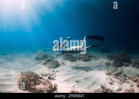 Attraktive Freitaucherin Frau mit Flossen tauchen tief unter Wasser im Meer. Stockfoto