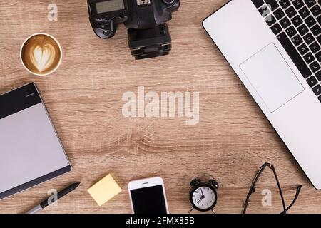 Termin für Fotografen Konzept. Draufsicht auf den Designer-Tisch mit pc-Laptop-Computer, Zeichentablett, Fotokamera, Handy-Gadget, Wecker, Stockfoto