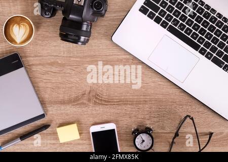 Termin für Fotografen Konzept. Draufsicht auf den Designer-Tisch mit pc-Laptop-Computer, Zeichentablett, Fotokamera, Handy-Gadget, Wecker, Stockfoto