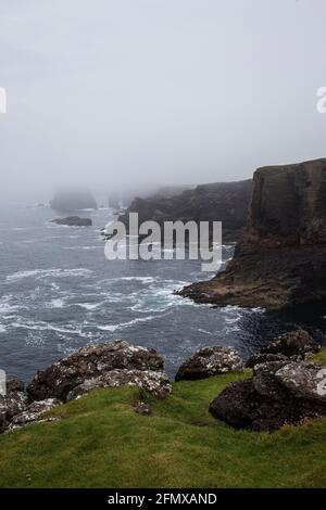 Neblige Küstenlandschaft bei Eshaness in Shetland an der westlichen Spitze von Northmavine mit spektakulärer Küstenlandschaft, schwarzen Klippen und Atlantischem Ozean Stockfoto