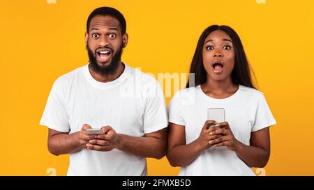 Porträt von überrascht schwarzen Paar mit Smartphones Stockfoto