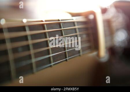 Die Hand eines Mannes auf dem Griffbrett einer Gitarre läuft mit den Fingern durch die Saiten und spannt die Akkorde. Instrumentalmusik, Gitarrenunterricht auf Noten Stockfoto