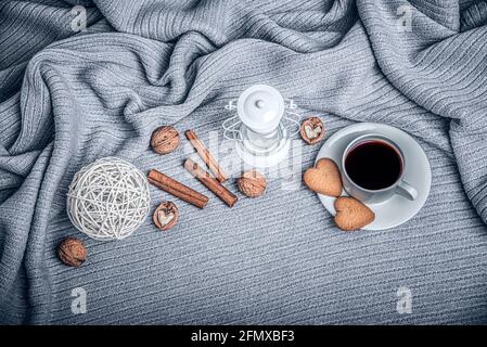 Schöne Plaid, eine Tasse mit Kaffee und Cookies auf einem Tisch mit Kerzen. Stockfoto