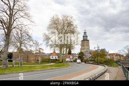 ZUTPHEN, NIEDERLANDE - 20. Apr 2021: Urbane, gewundene Asphaltstraße mit der holländischen hanseatischen mittelalterlichen Stadt Zutphen und dem Walburgiskerk-Turm im Hintergrund Stockfoto