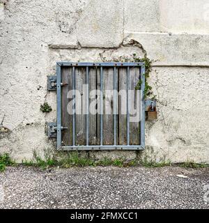 Metallstangen und Vorhängeschloss über ausgediente, vernagelten Fenstern Stockfoto