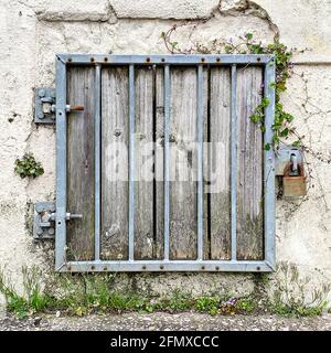 Metallstangen und Vorhängeschloss über ausgediente, vernagelten Fenstern Stockfoto