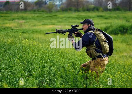 Airsoft-Spieler in Militäruniform zielt auf den Feind Stockfoto