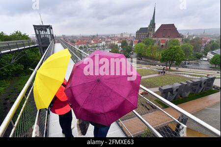 Erfurt, Deutschland. Mai 2021. Die Besucher der Bundesgartenschau (BUGA) stehen bei Regenwetter auf dem Petersberg mit Blick auf die Stadt mit dem Mariendom und der St. Severus Kirche. Vom 23. April bis zum 10. Oktober 2021 findet das Sommerfest mit Gartenbau-Schaufenster auf zwei Ausstellungsflächen in Erfurt statt. Darüber hinaus wird es 25 BUGA-Außenstandorte in ganz Thüringen geben. Quelle: Martin Schutt/dpa-Zentralbild/dpa/Alamy Live News Stockfoto