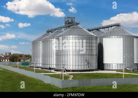 Szenischer Blick auf große, moderne Getreidespeicher-Getreidespeicher aus Stahl vor blauem Himmel. Agrarindustrie Ackerland ländliche Industrie Stockfoto