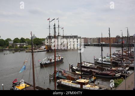 Segelboote mit Liegeplätzen und nationales Schifffahrtsmuseum und Nachbildung des Schiffs Amdterdam im Hintergrund in Amsterdam Stockfoto