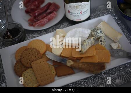 Essen Und Trinken / Käse- Und Weinnacht / Essen Konzept - Nahaufnahme einer Käseplatte, mit herzhaften Crackern und Eine Flasche Rotwein Stockfoto