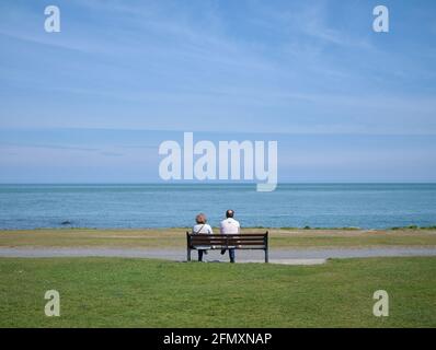 Ein Paar sitzt auf einer Bank mit Blick auf das Meer bei Skerries im Norden der Grafschaft Dublin, Irland. Stockfoto