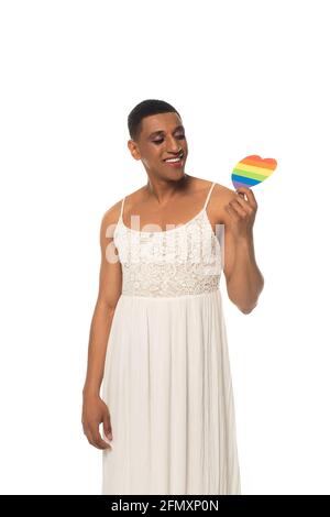 Fröhlicher afroamerikanischer Transvestit-Mann in Kleid mit lgbt-Farben Papier Herz isoliert auf weiß Stockfoto