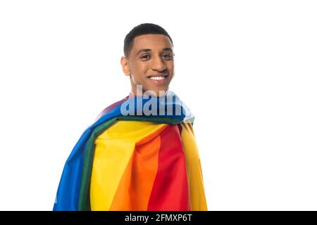 Fröhlicher afroamerikanischer Mann, eingewickelt in lgbt-Flagge, der die Kamera isoliert auf Weiß ansieht Stockfoto