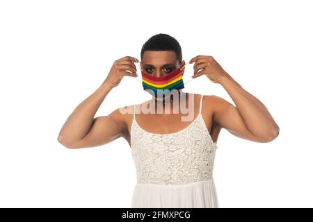 afroamerikanischer Transvestit-Mann, der eine medizinische Maske mit lgbt-Farben aufsetzt Isoliert auf Weiß Stockfoto