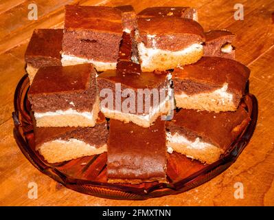 Drei farbige Brownies mit süßem Hüttenkäse in der Mitte, in mehrere Schichten auf einer Glasplatte gestapelt Stockfoto