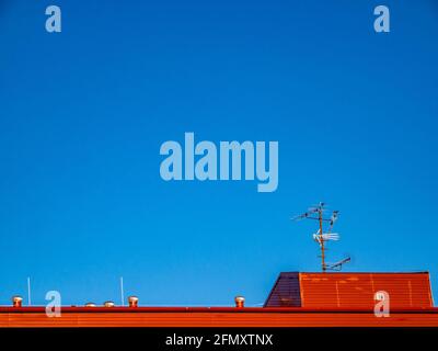 Das Dach des Gebäudes mit Lüftung und TV-Antennen, unter dem strahlend blauen Himmel. Stockfoto