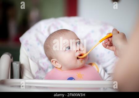 Mutter füttert ihr kleines Mädchen mit einem Löffel. Babynahrung Stockfoto