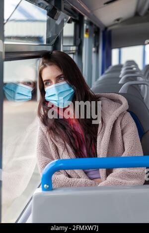 Eine Frau, die im Bus sitzt und ihren Kopf dagegen ruht Das Fenster Stockfoto