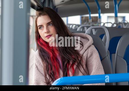 Eine junge Frau fährt mit dem Bus und starrt ruhig aus Das Fenster Stockfoto
