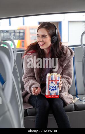 Eine junge Frau, die Popcorn auf dem Rücksitz von isst Ein Bus Stockfoto