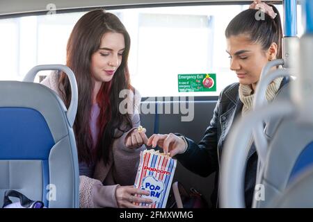 Zwei Freunde, die Popcorn auf dem Rücksitz eines genießen Bus Stockfoto
