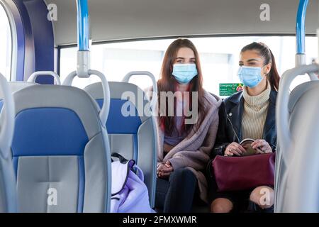 Zwei junge Frauen sitzen auf dem Rücksitz eines Bus Stockfoto