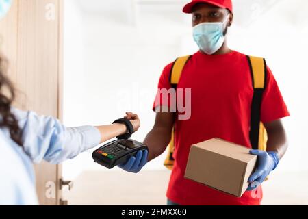 Schwarzer Mann mit POS-Maschine-Client, der mit Smart Watch bezahlt Stockfoto