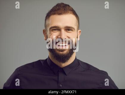Studio-Porträt eines stilvollen bärtigen jungen Mannes mit einem glücklichen Lächeln Auf seinem freundlichen Gesicht Stockfoto