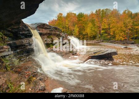 Ein Wasserfall sendet seidige Streamer stromabwärts vor dem Hintergrund von Wälder reich an Herbstfarben Stockfoto