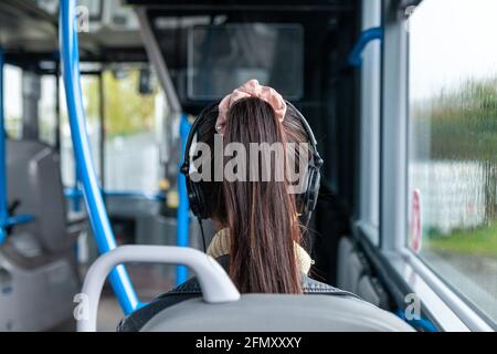 Eine Frau mit ihren Haaren in einem Pferdeschwanz, die Kopfhörer trägt, von hinten Stockfoto