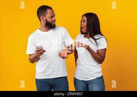 Schwarze Frau, die mit dem Mobiltelefon einen Freund anbrüllt Stockfoto