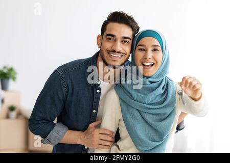 Emotionale junge Dame im Hijab, die den Schlüssel aus dem Haus zeigt Stockfoto