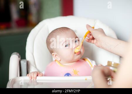 Mutter füttert ihr kleines Mädchen mit einem Löffel. Babynahrung Stockfoto