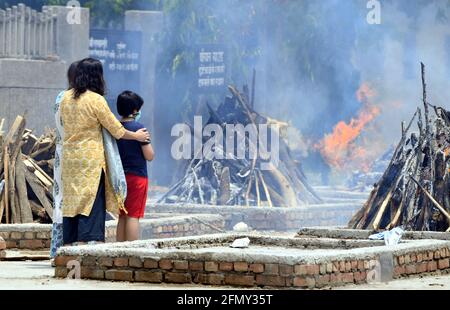 Neu-Delhi, Indien. Mai 2021. Familienmitglieder betrachten die Scheiterhaufen für ein COVID-19-Opfer im Krematorium Sarai Kale Khan in Neu-Delhi, Indien, 12. Mai 2021. Quelle: Partha Sarkar/Xinhua/Alamy Live News Stockfoto