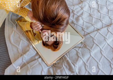Die junge Frau untersucht ihre Haut im Spiegel. Home Care-Konzept. Problemhaut im Gesicht Stockfoto