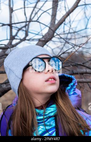 Teenager-Mädchen in verspiegelter Sonnenbrille blickt in den Himmel. Wellness-Konzept Stockfoto