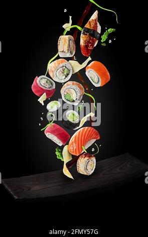 Sushi mit Garnierungen und Sojasauce über dem Teller Schwarzer Hintergrund Stockfoto