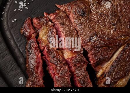 Nahaufnahme von in Scheiben geschnittenem, saftigem Rind-Striploin-Steak auf Holzbrett Stockfoto