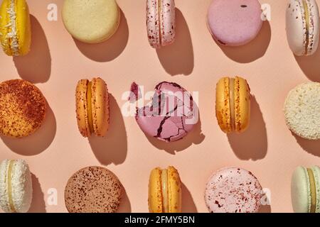 Blick von oben auf ganze Macarons und einer in der Mitte gebissen Auf rosa Hintergrund Stockfoto