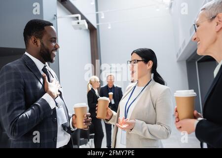 Lächelnde, multiethnische Kollegen aus der Geschäftswelt, die Kaffee trinken, um sich zu unterhalten Besprechung Stockfoto