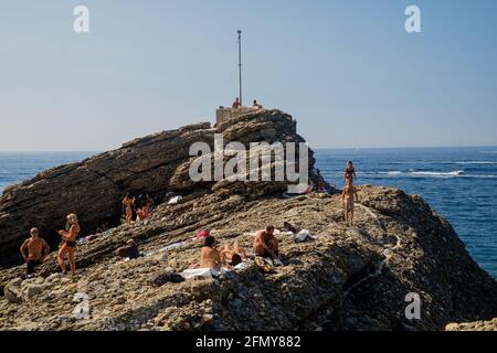 Die Menschen sonnen sich an einem felsigen Strand in Ligurien. Diese einzigartige Lage ist Punta Chiappa in der Nähe von Camogli. Stockfoto